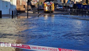 A view of flood water behind a cordon. There is a fire engine parked on the opposite side of the water.