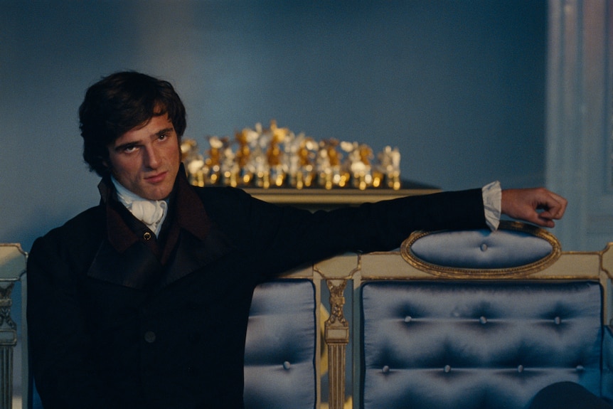 A man in a suit sits on a light blue couch