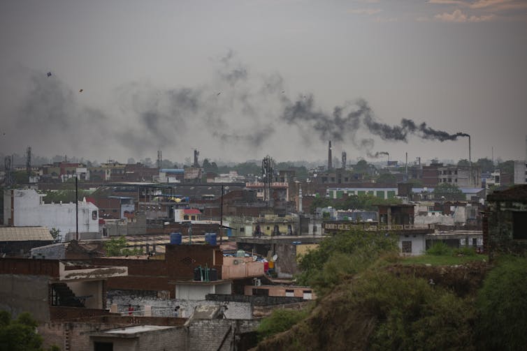 black smoke rises from tall chimneys above a cityscape