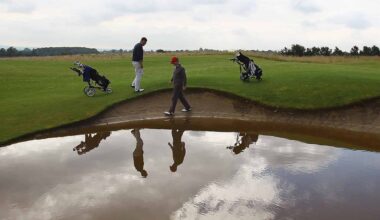 John Jacobs (L) of Cumberwell Park Golf Club looks for his ball in a flooded bunker with Richard Dinsdale of Parc Golf Academy during the Lombard Challenge Regional Qualifier at Cumberwell Park Golf Club on August 6, 2012 in Bath, England