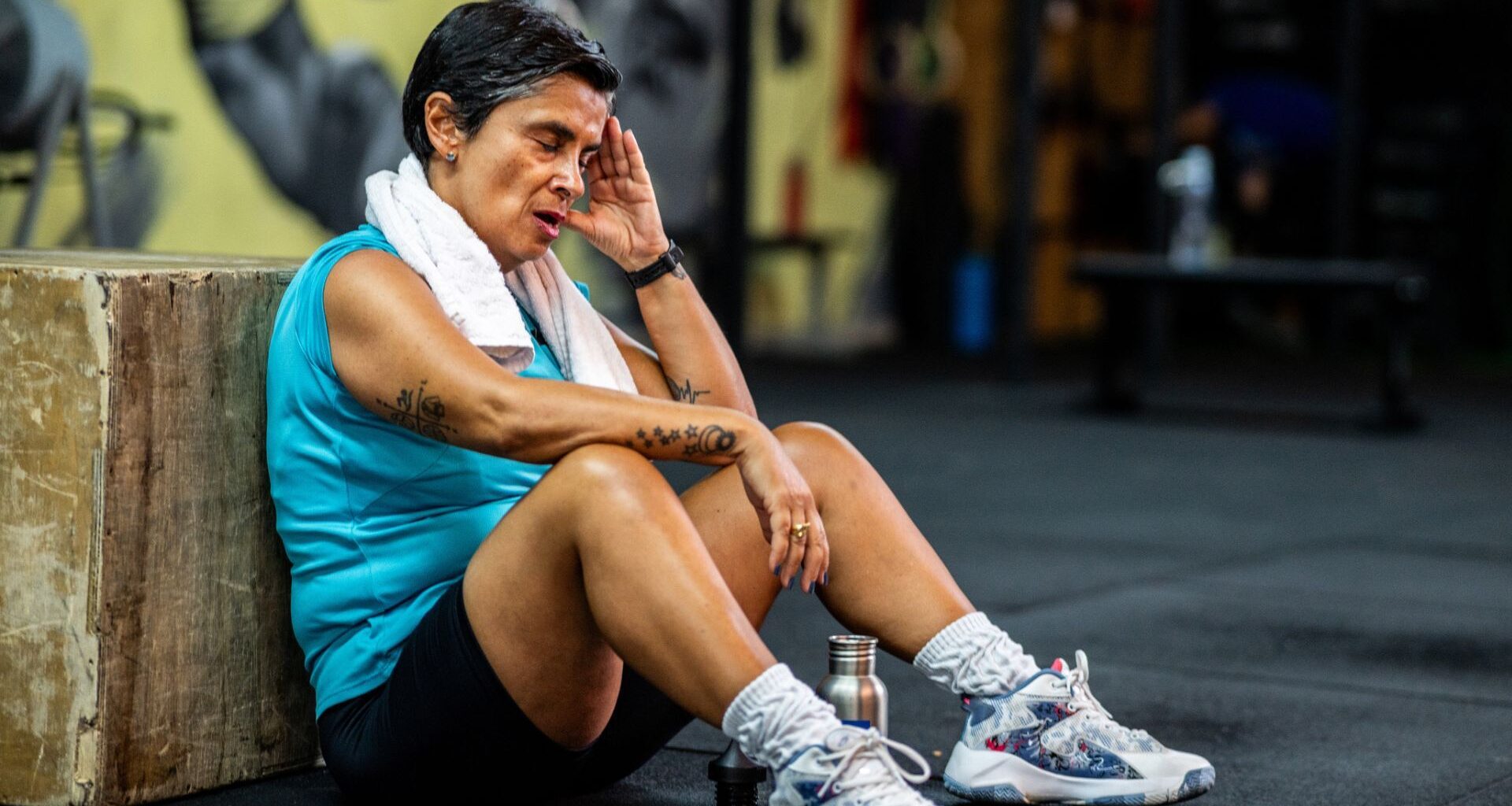 senior woman sits on the floor in the gym to take a rest