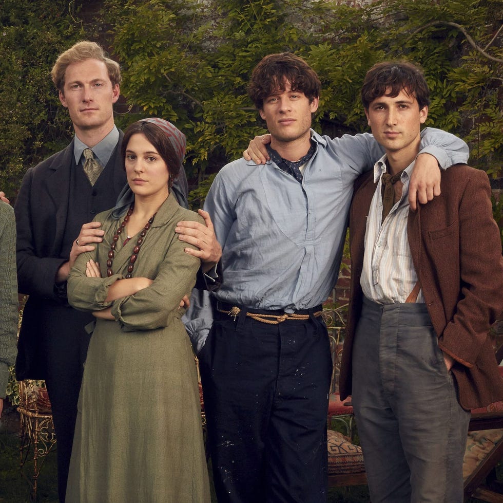 group portrait of six people dressed in vintage clothing in a garden setting