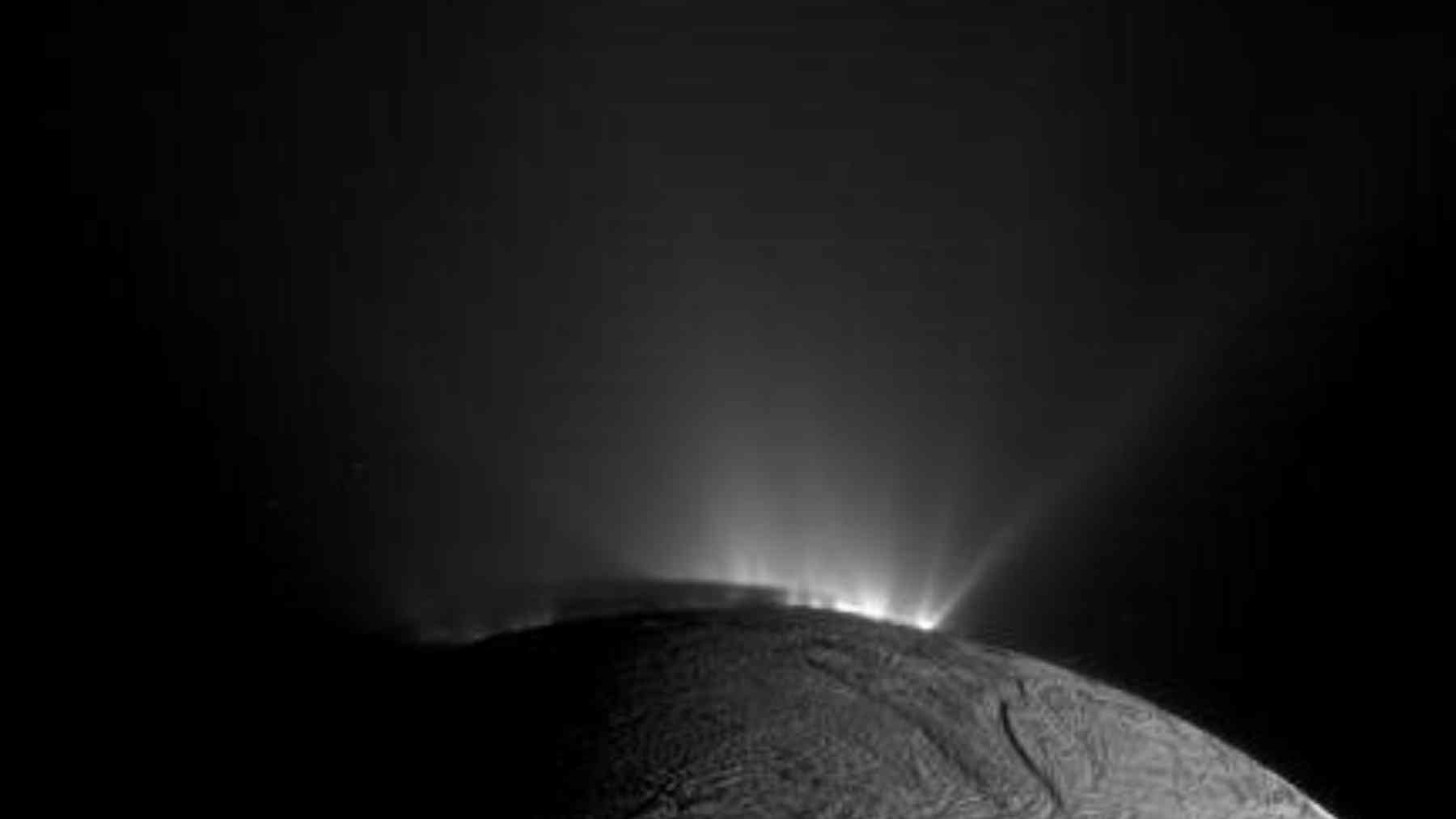 Backlit plumes erupt from Saturn’s icy moon Enceladus in a Cassini spacecraft image.