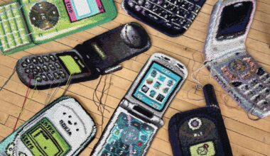 Fiber art pieces by Nicole Nikolich of dated flip phones, laid out on a hardwood floor