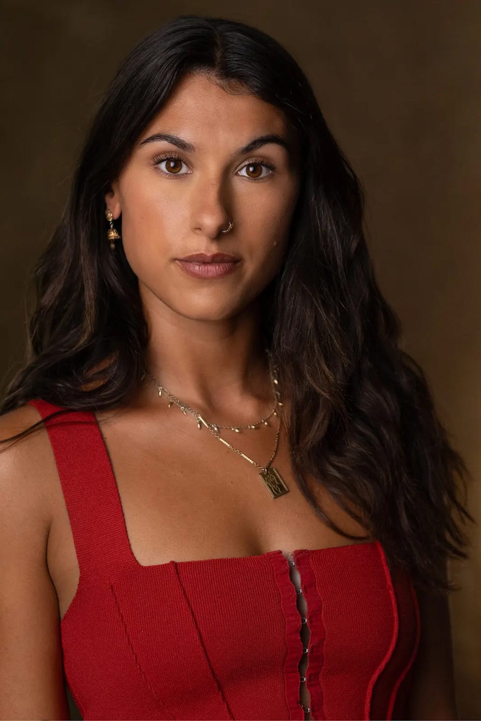 portrait featuring a person wearing a red outfit with layered necklaces