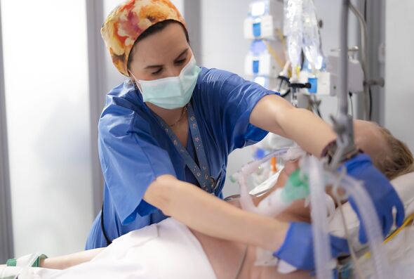 Nurse adjusting ventilator of patient in intensive care unit