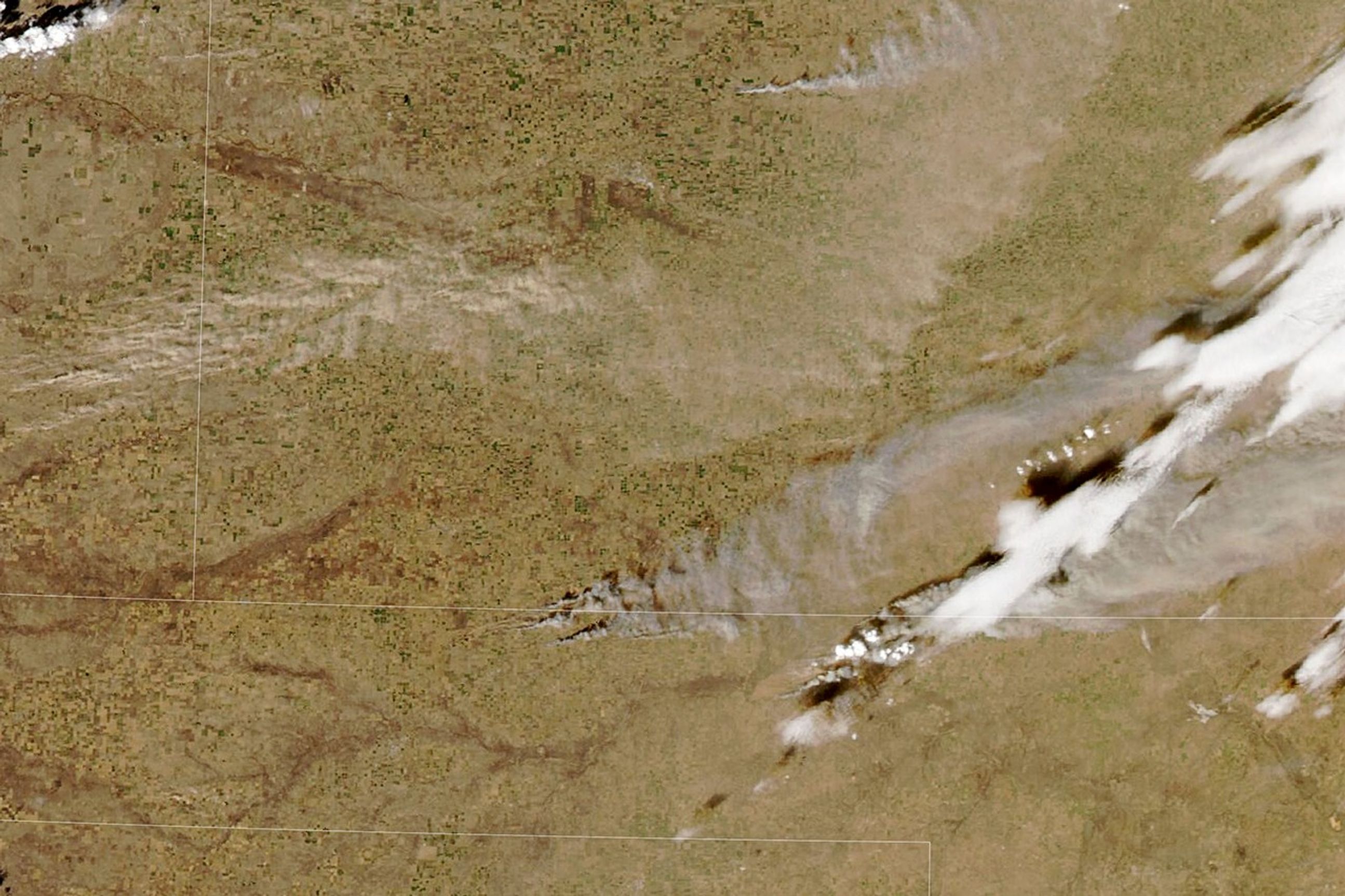 Plumes of gray smoke drift east-northeast from several grass and brush fires in the Oklahoma Panhandle. To the north, tan clouds of wind-borne dust cover portions of Kansas.