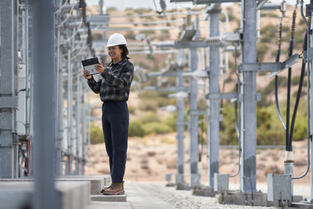 Woman in hard hat amid energy towers.