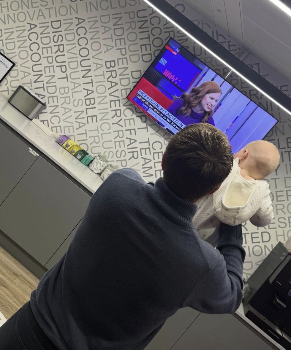 Patrick Christys holds up George to show Emily Carver on TV