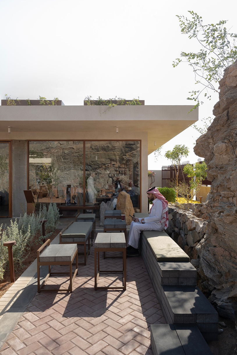 open planted courtyard organizes a café carved directly into rock in saudi arabia