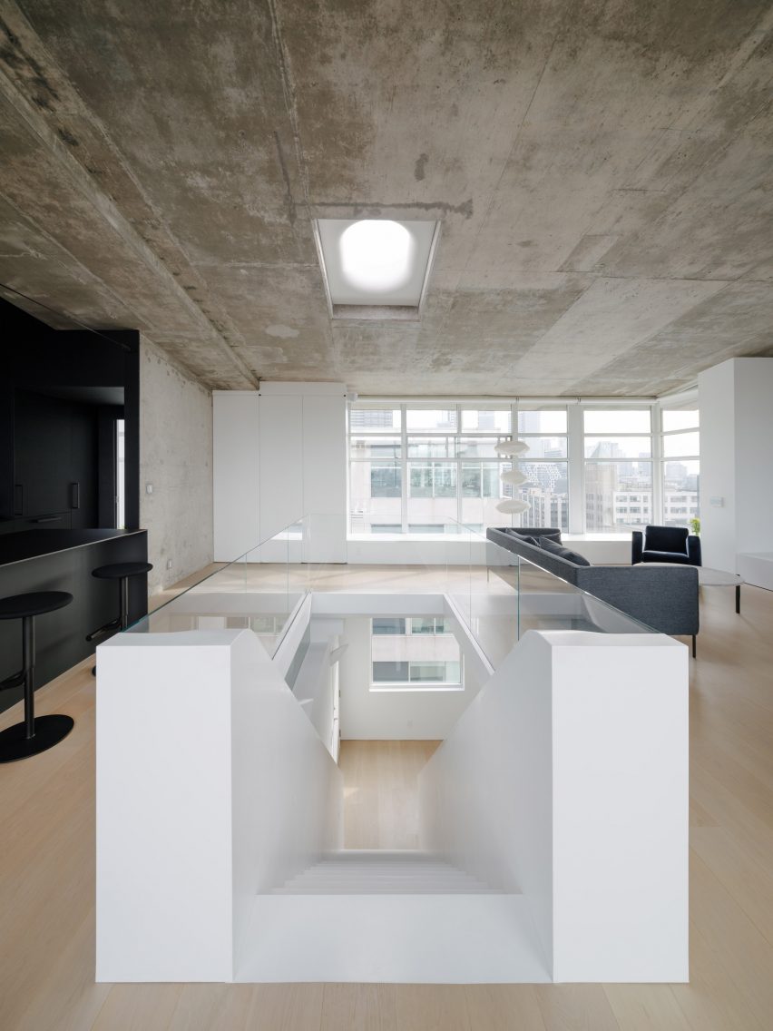 A white Corian staircase bifurcates a duplex apartment interior