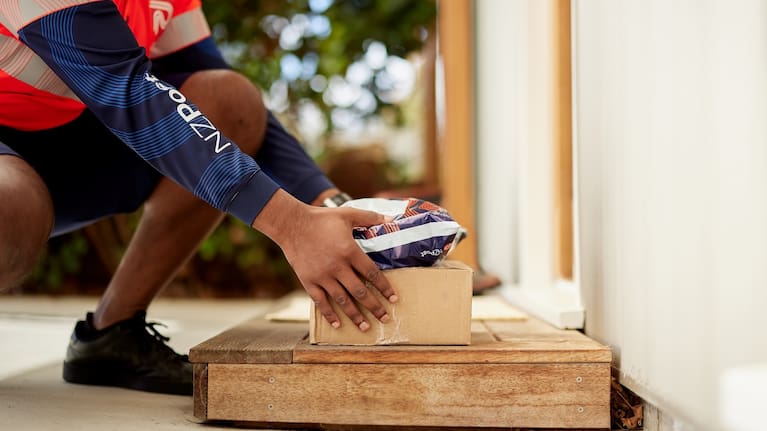 Postal worker placing two packages on a doorstep. 