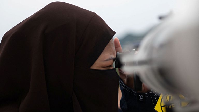 A woman looks through a telescope trying to see the crescent moon in Indonesia. Pic: Reuters