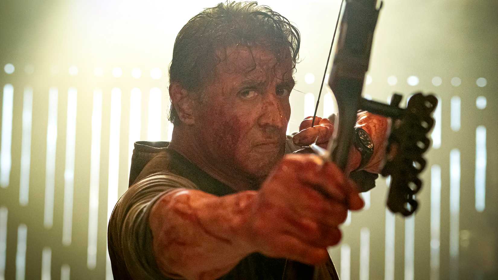 Sylvester Stallone as Rambo aiming a bow and arrow toward the camera in Rambo: Last Blood