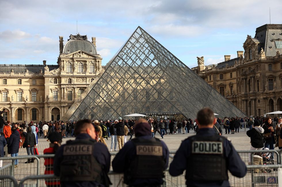 \u200bPolice officers stand guard near the Louvre Pyramid in Paris