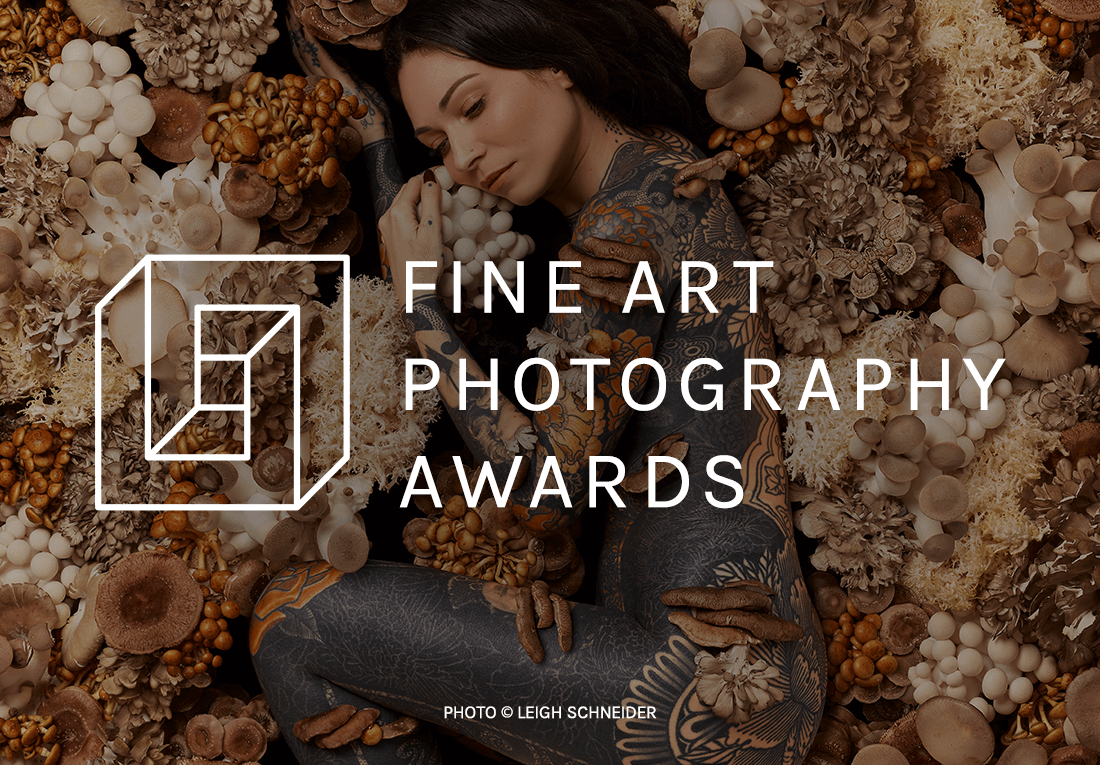 A person with intricate tattoos lies amidst an artistic arrangement of various mushrooms and floral elements, featuring award logo