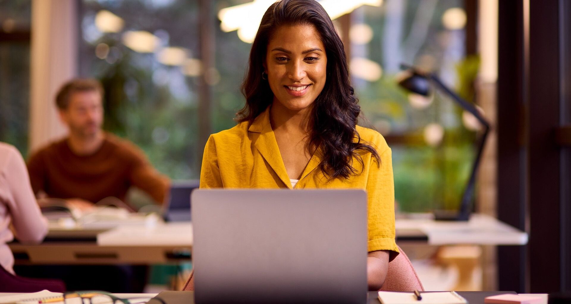 A young woman is working on a Windows 11 laptop in a relaxed office space