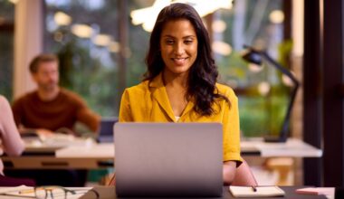 A young woman is working on a Windows 11 laptop in a relaxed office space