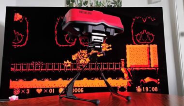 Switch Virtual Boy on woodgrain table with TV in backdrop and Virtual Boy Wario Land on screen.