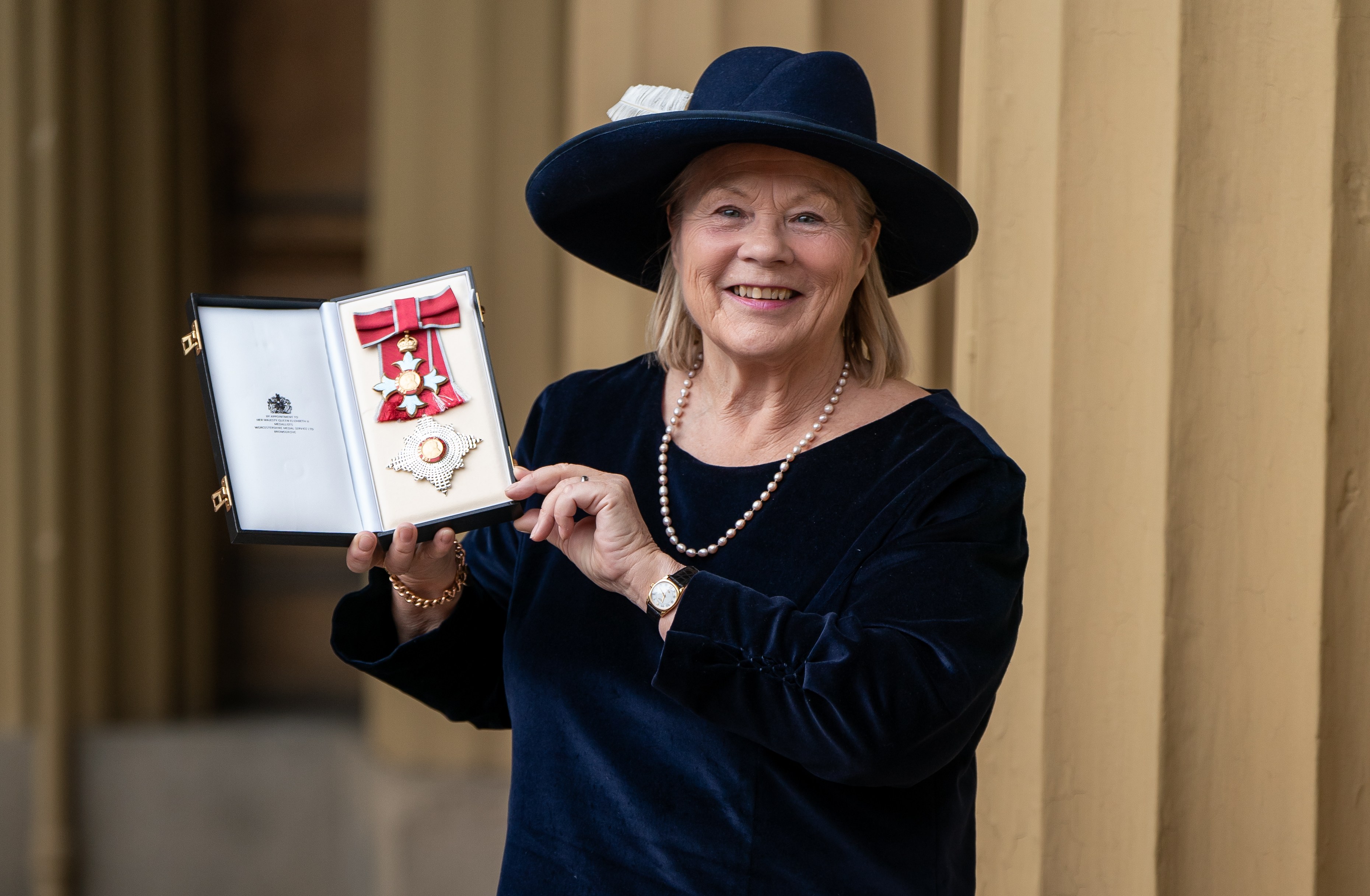 Dame Ann Limb holding her Dame Commander of the British Empire medal.