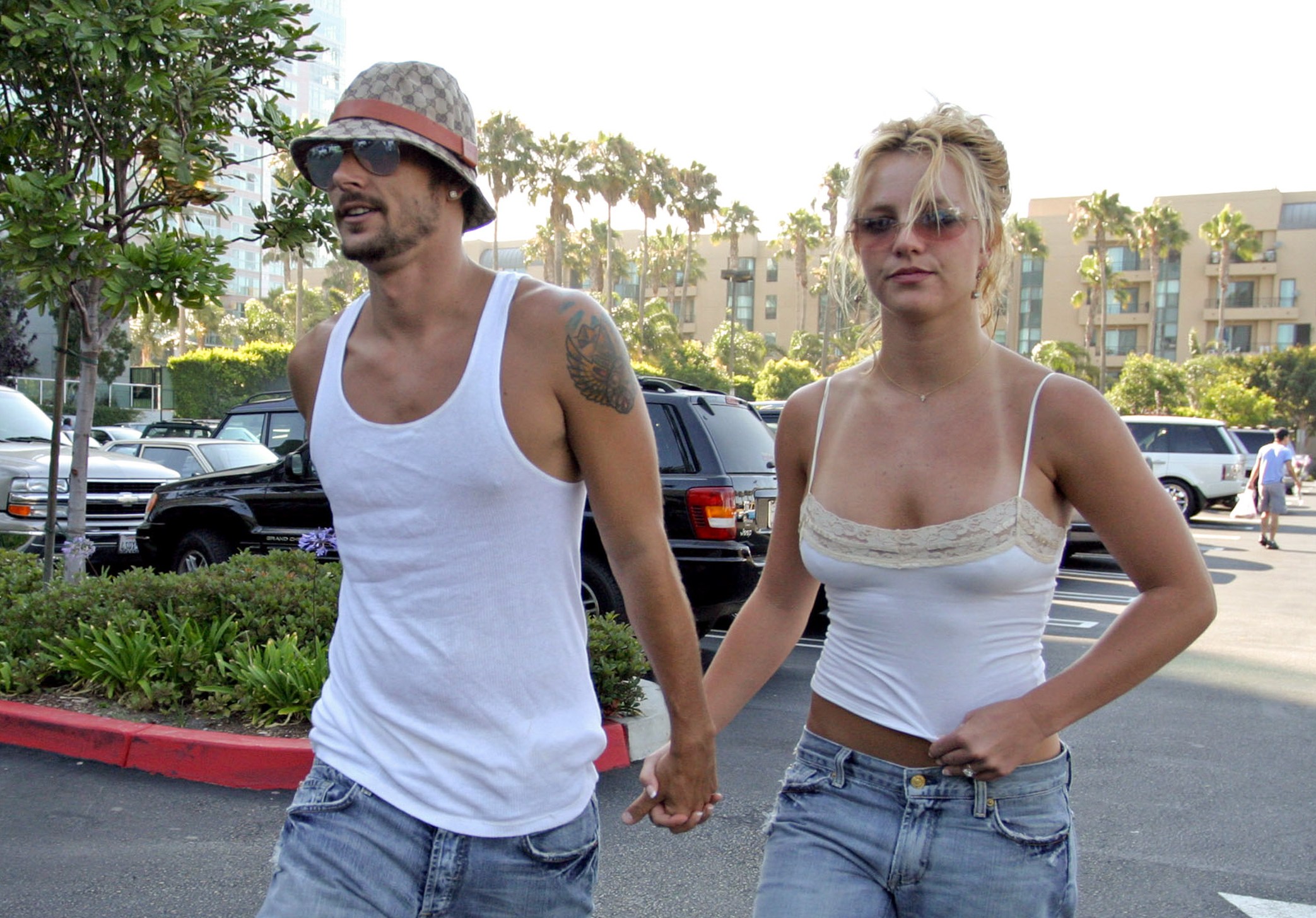 Kevin Federline and Britney Spears holding hands in a parking lot.
