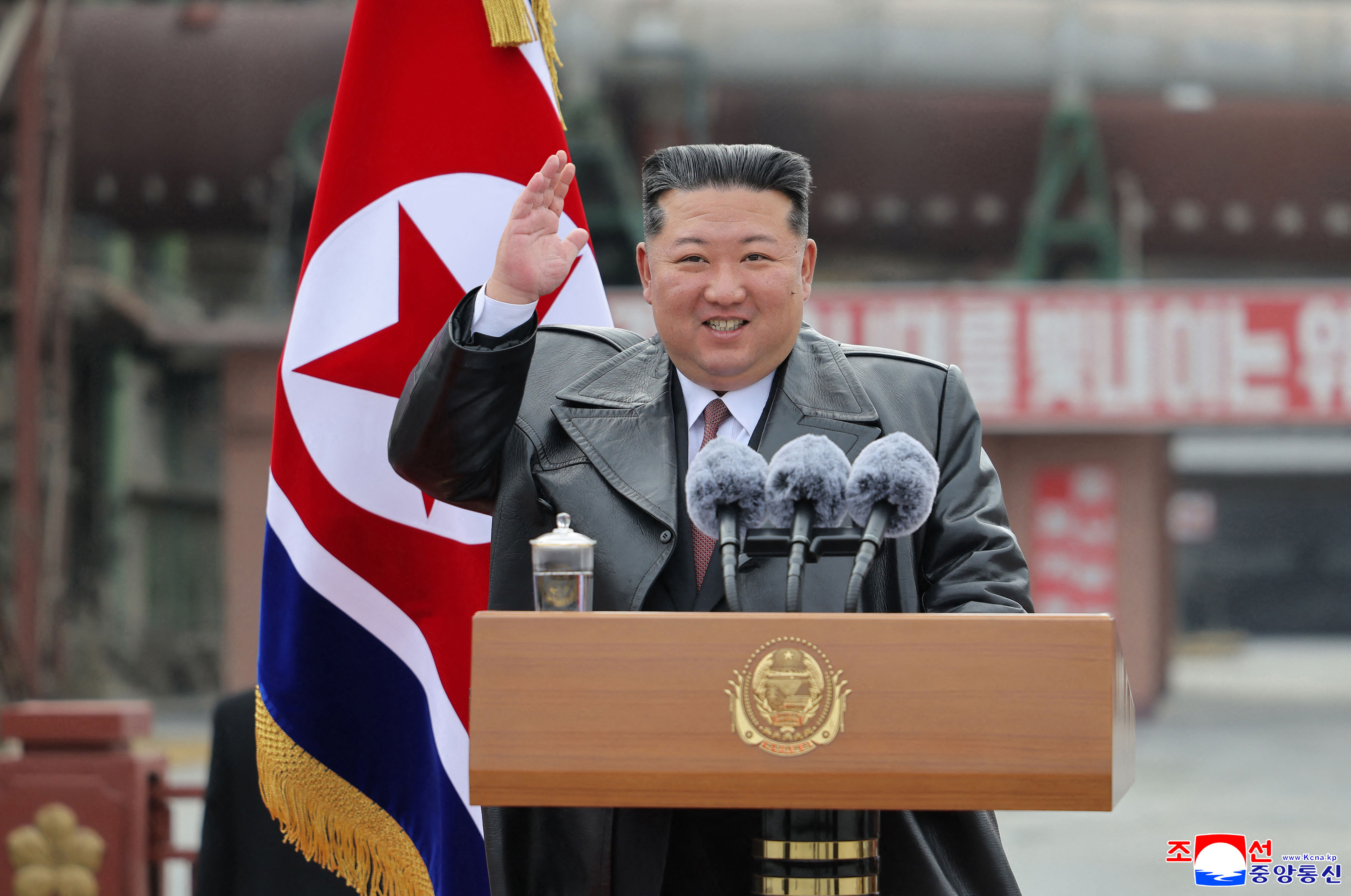 North Korean leader Kim Jong Un delivering a speech from a podium, waving his right hand.