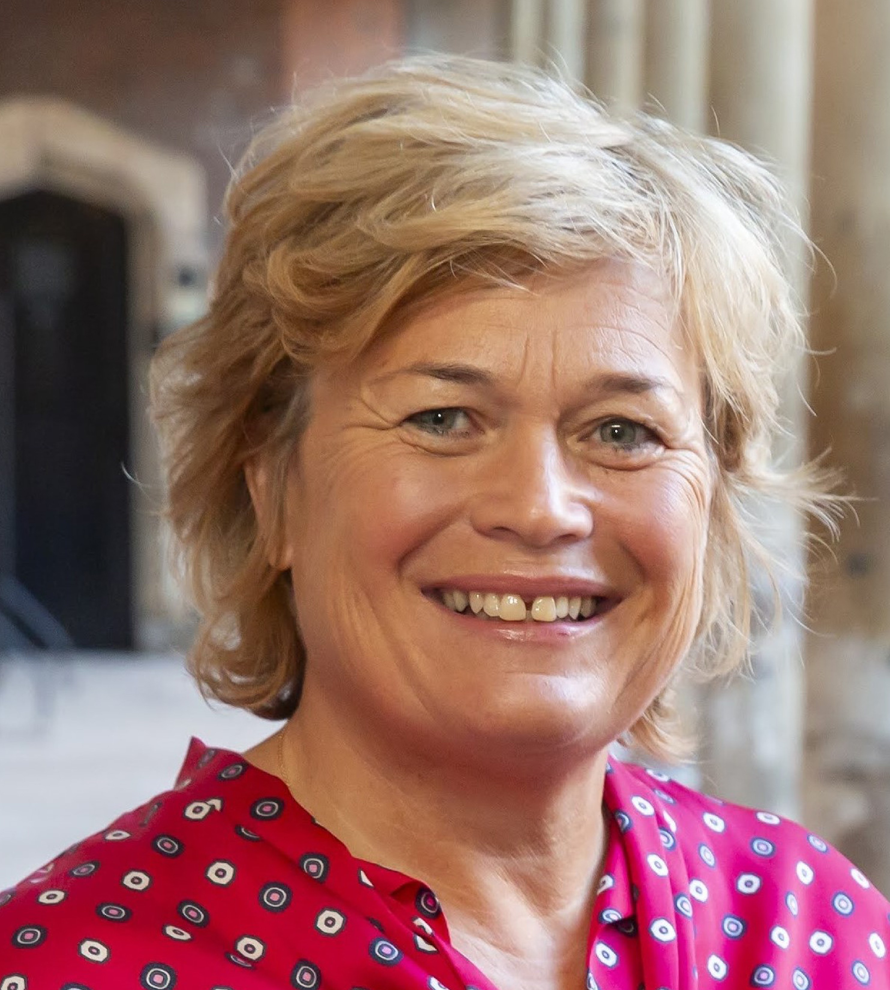 Collage of two headshots of blonde women smiling, one wearing a red patterned top and the other wearing a light blue jacket over a patterned top with a pearl necklace.