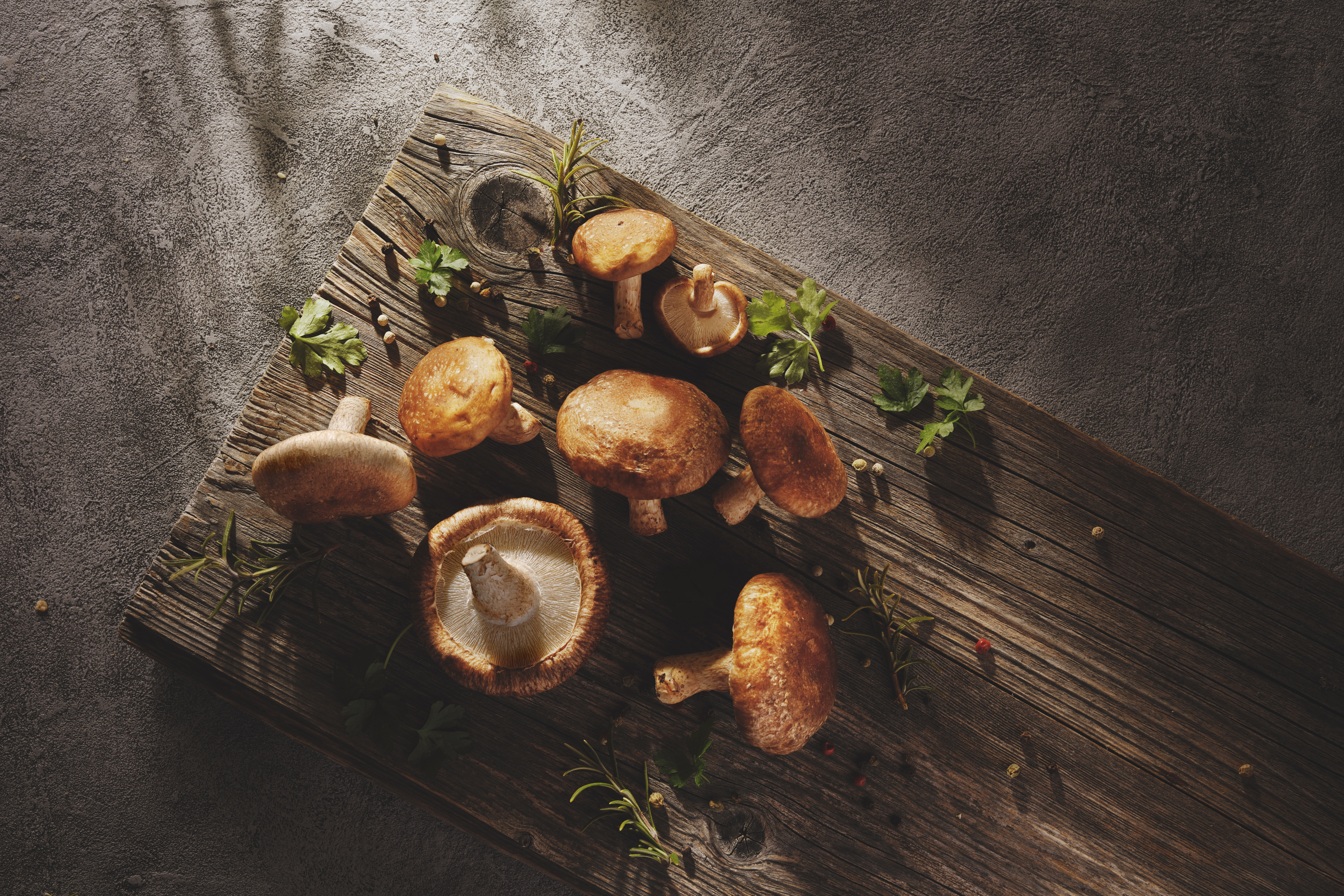 Shiitake mushrooms with spices and herbs on a rustic wooden background.