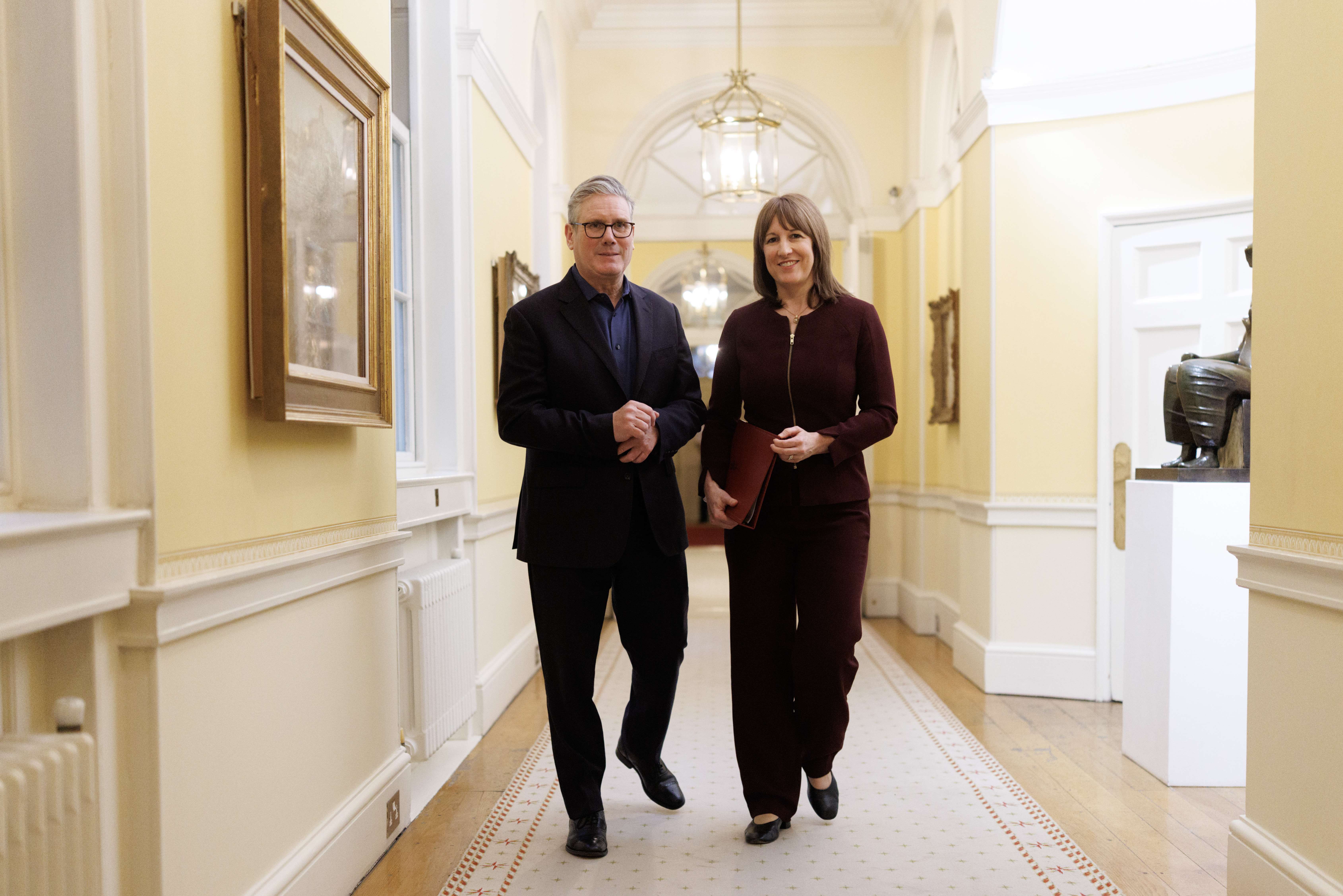 Prime Minister Keir Starmer and Chancellor of the Exchequer Rachel Reeves walk down a hallway.