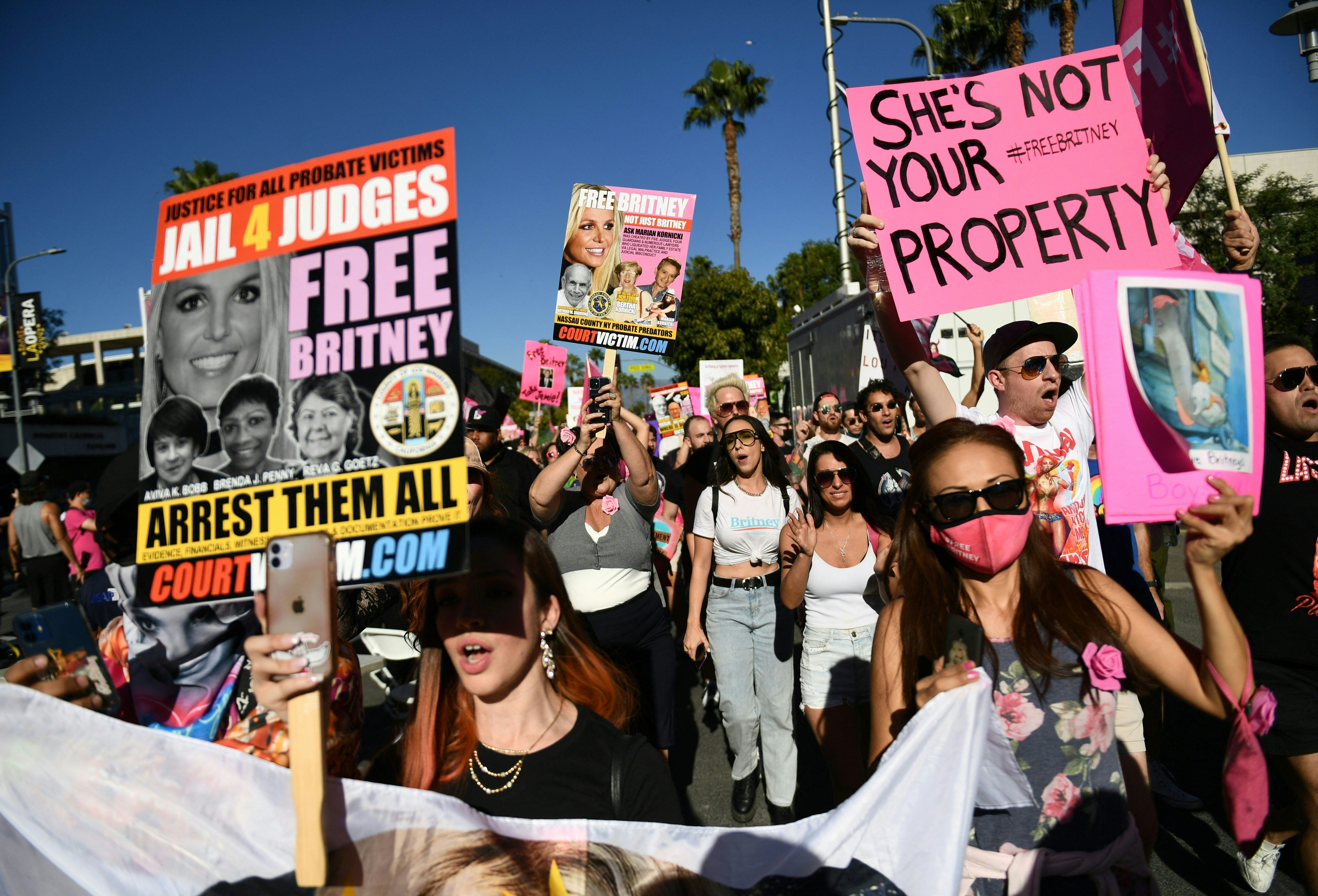 Supporters of the "FreeBritney" movement rally outside a courthouse, holding signs demanding justice for Britney Spears and other probate victims.