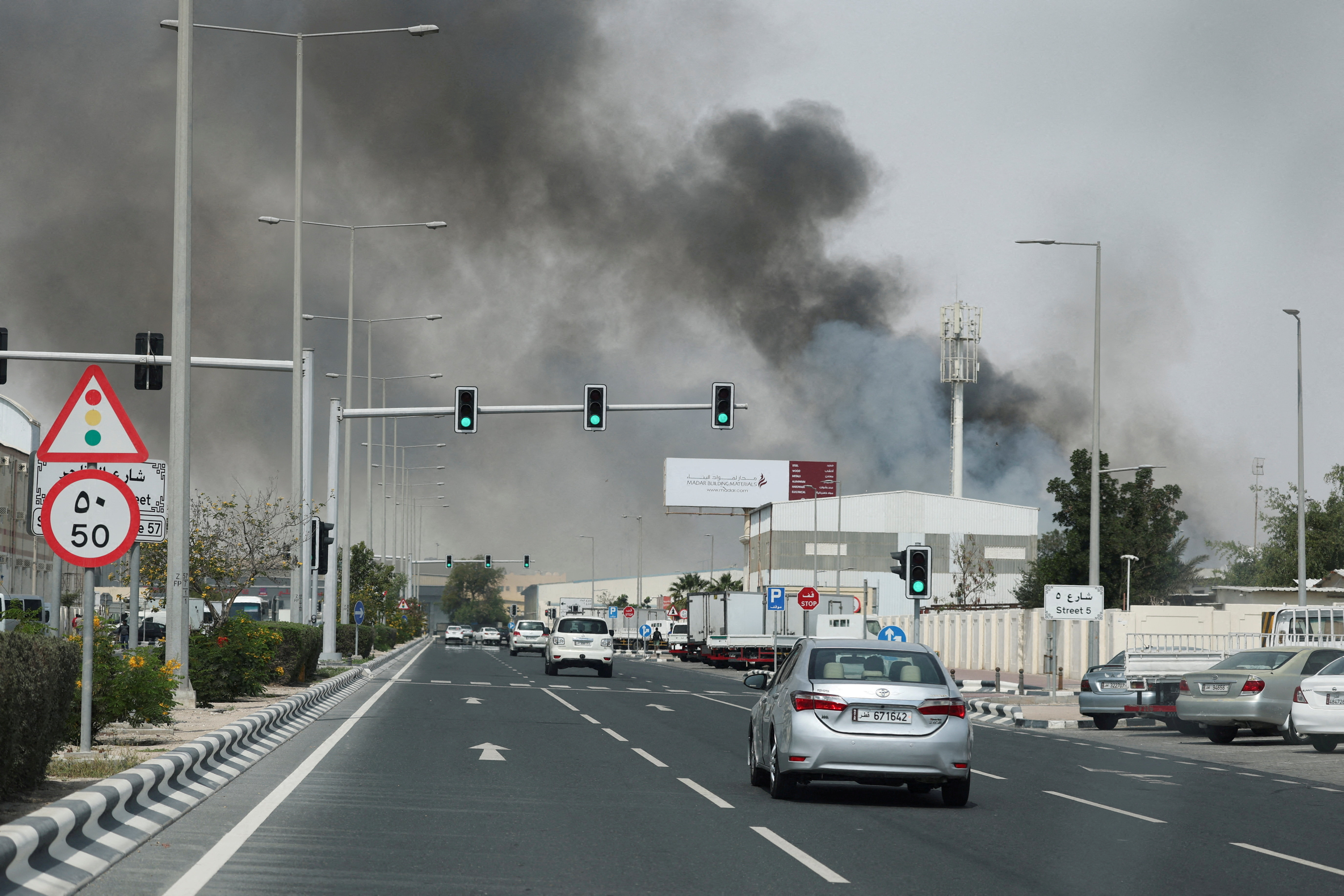 Smoke rising over buildings and a highway in Doha, Qatar.
