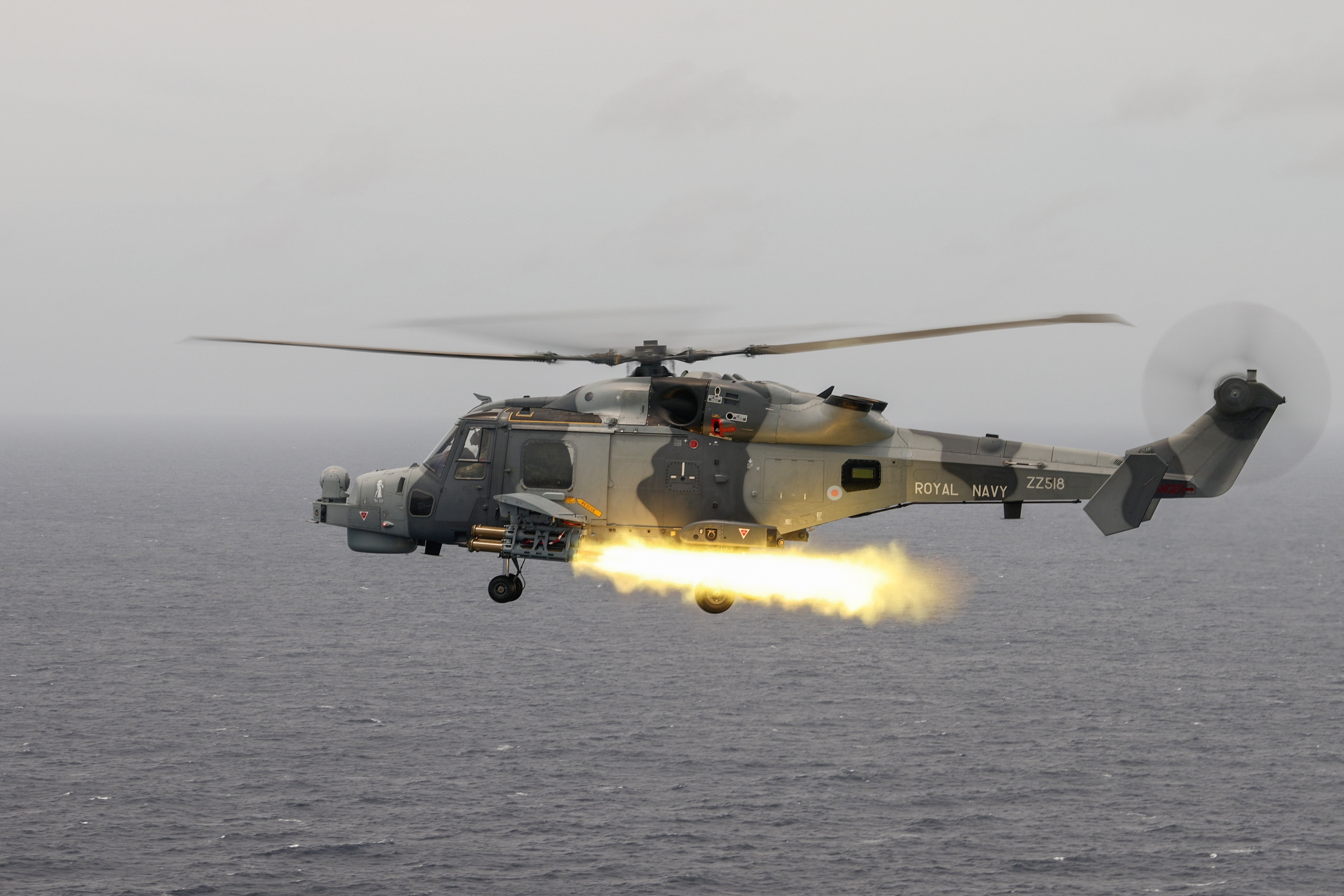 A Royal Navy Wildcat helicopter firing a Martlet missile over the ocean.