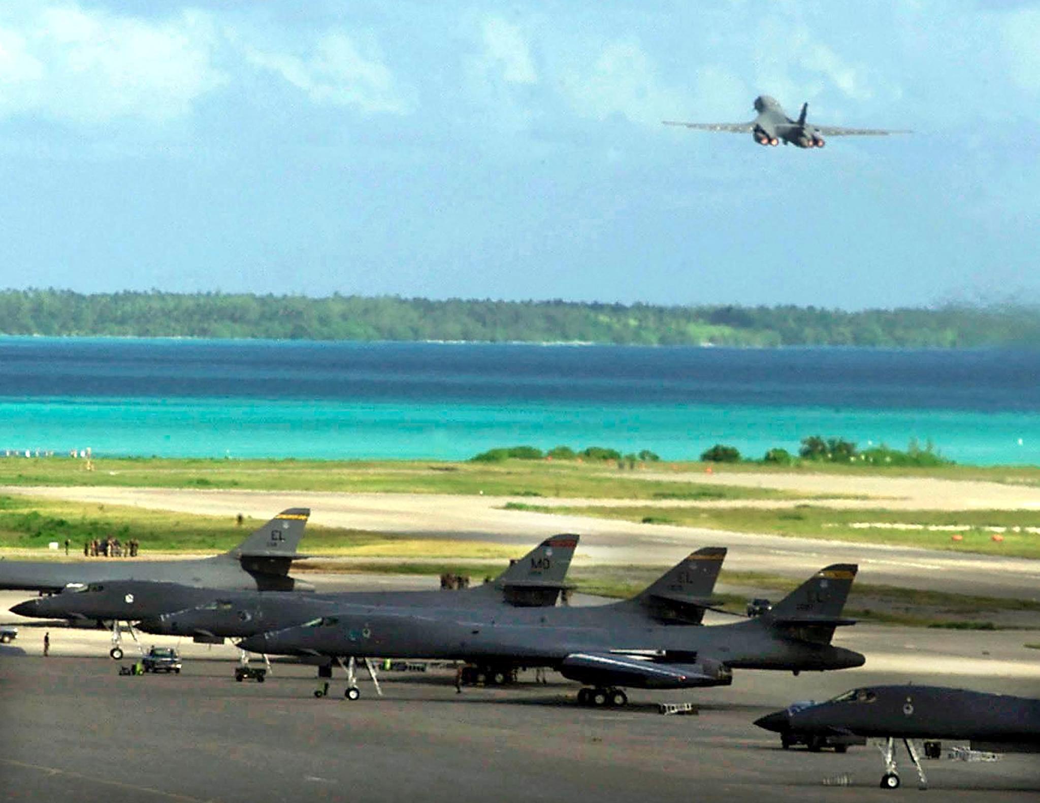 A B-1B bomber takes off from Diego Garcia military base while other bombers are parked on the tarmac.