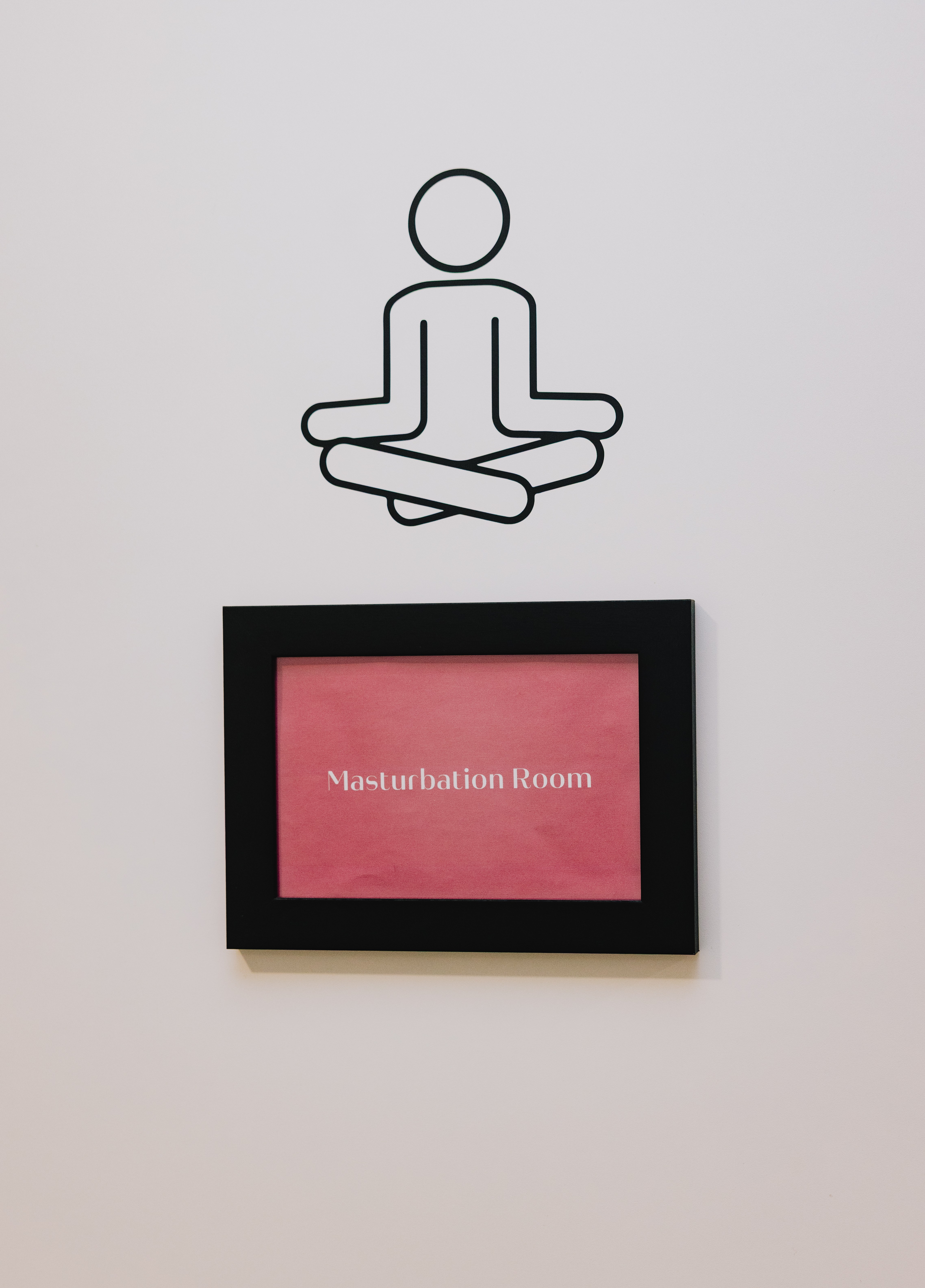 A wall sign for a "Masturbation Room" with a meditating figure above it.