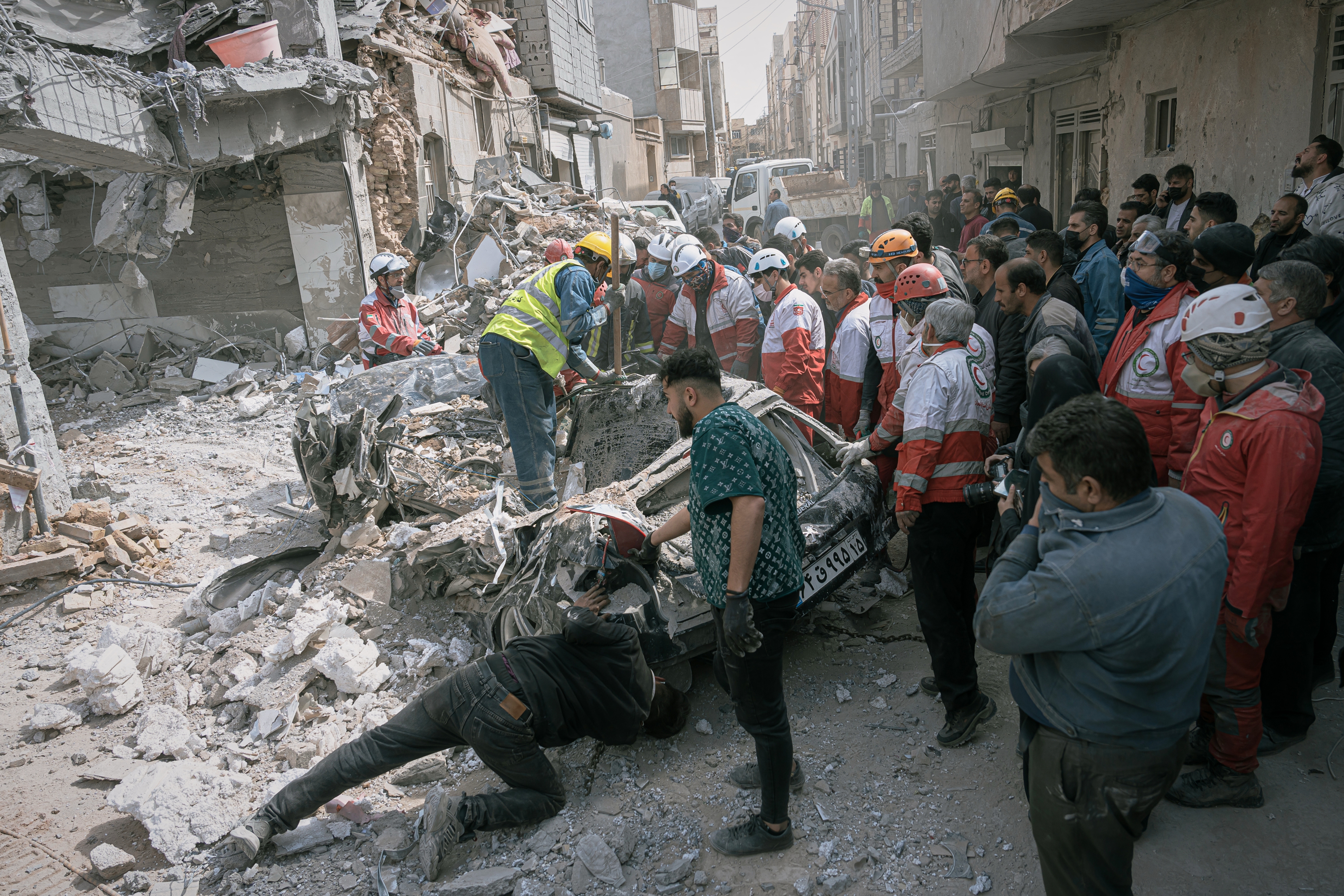 First responders inspect a destroyed car at the site of a residential building hit in an overnight strike in Tabriz, Iran.
