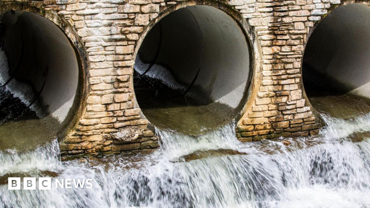 Water flows out of three openings of underground pipes. The pipes are surrounded by lightly coloured brickwork.