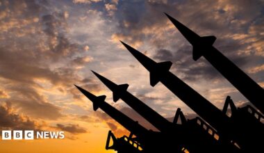 Silhouettes of four missiles pointing upwards against a cloudy skyline