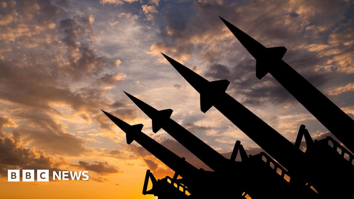 Silhouettes of four missiles pointing upwards against a cloudy skyline