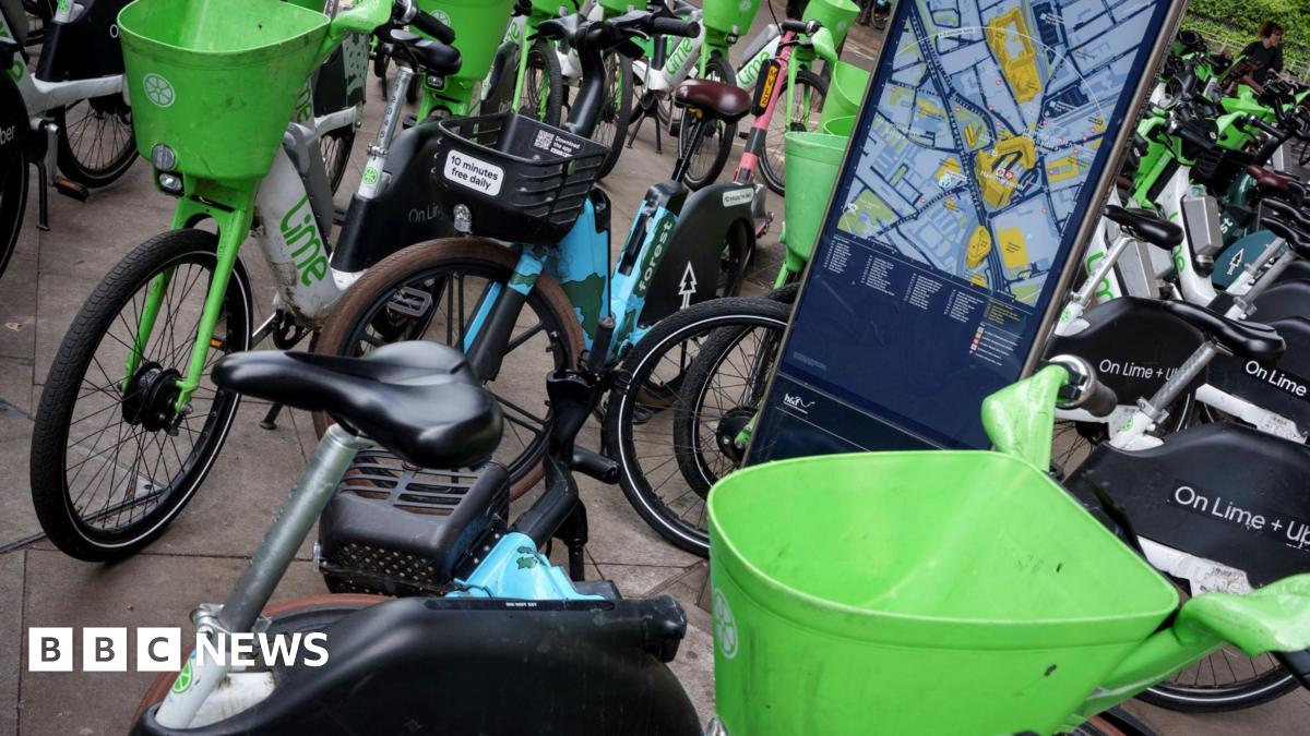 Lots of blue and green e-bikes parked up and a screen showing Hammersmith on a map