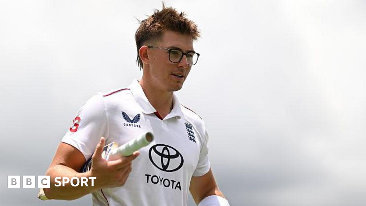 Asa Tribe of the England Lions walking off the field with a bat tucked in between his right arm.