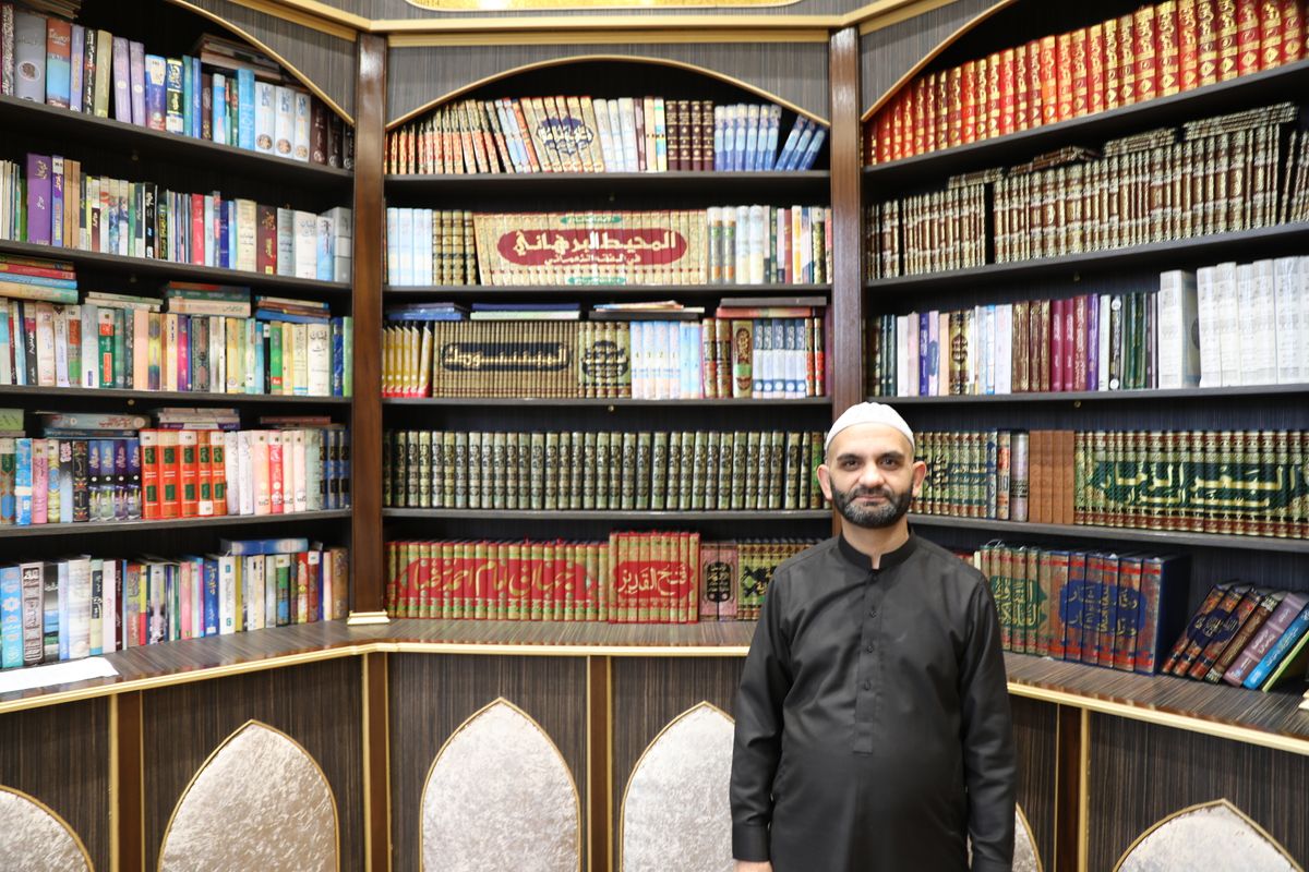 Manzoor Hussain in front of a book shelf 