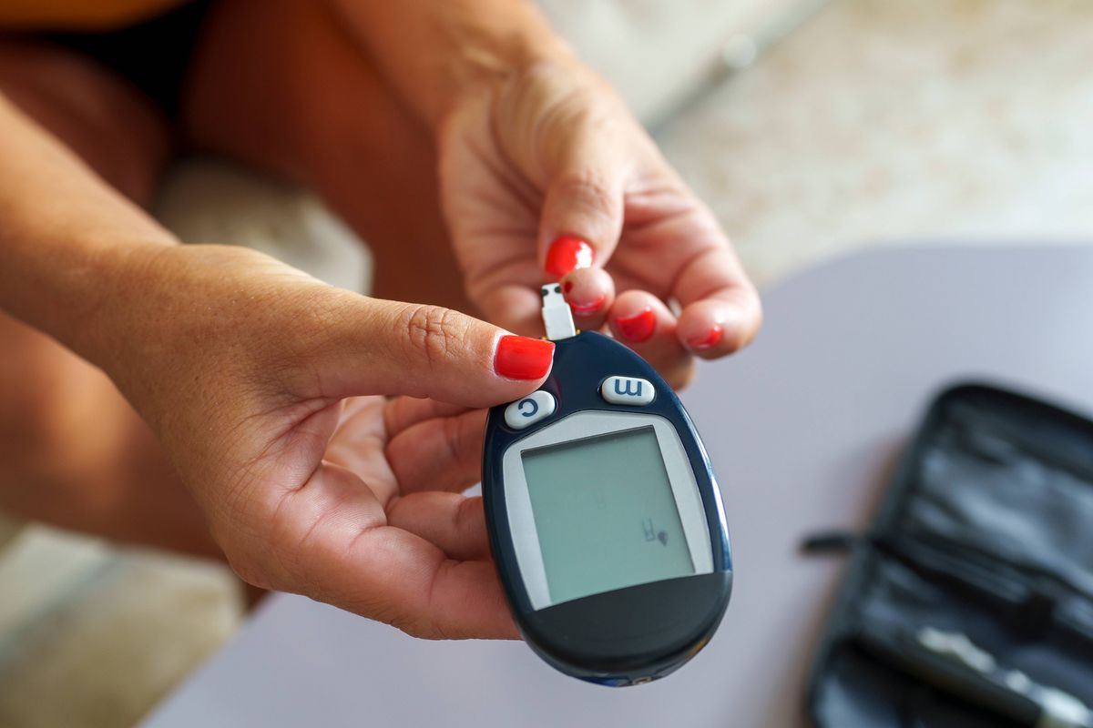 Middle-aged woman doing a blood sugar test. Adult woman in her 40s using sugar blood test to check the sugar level in blood stream.
