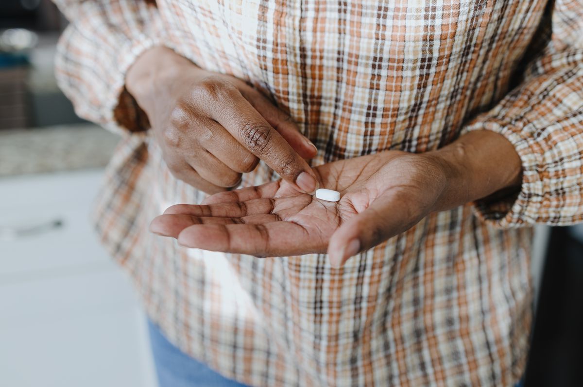 Close-up of unrecognizable woman holding a single pill in the palm of her hand