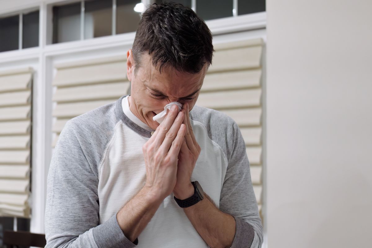 Close-up of mid adult man with cold/flu blowing his nose