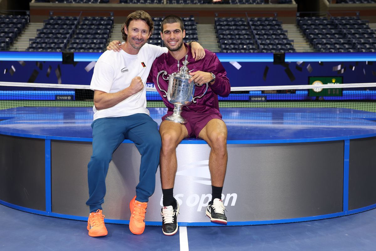 Carlos Alcaraz of Spain poses with his trophy next to his coach Juan Carlos Ferrero after defeating Jannik Sinner of Italy during their Men's Singles Final match on Day Fifteen of the 2025 US Open at USTA Billie Jean King National Tennis Center on September 07, 2025 in New York City.