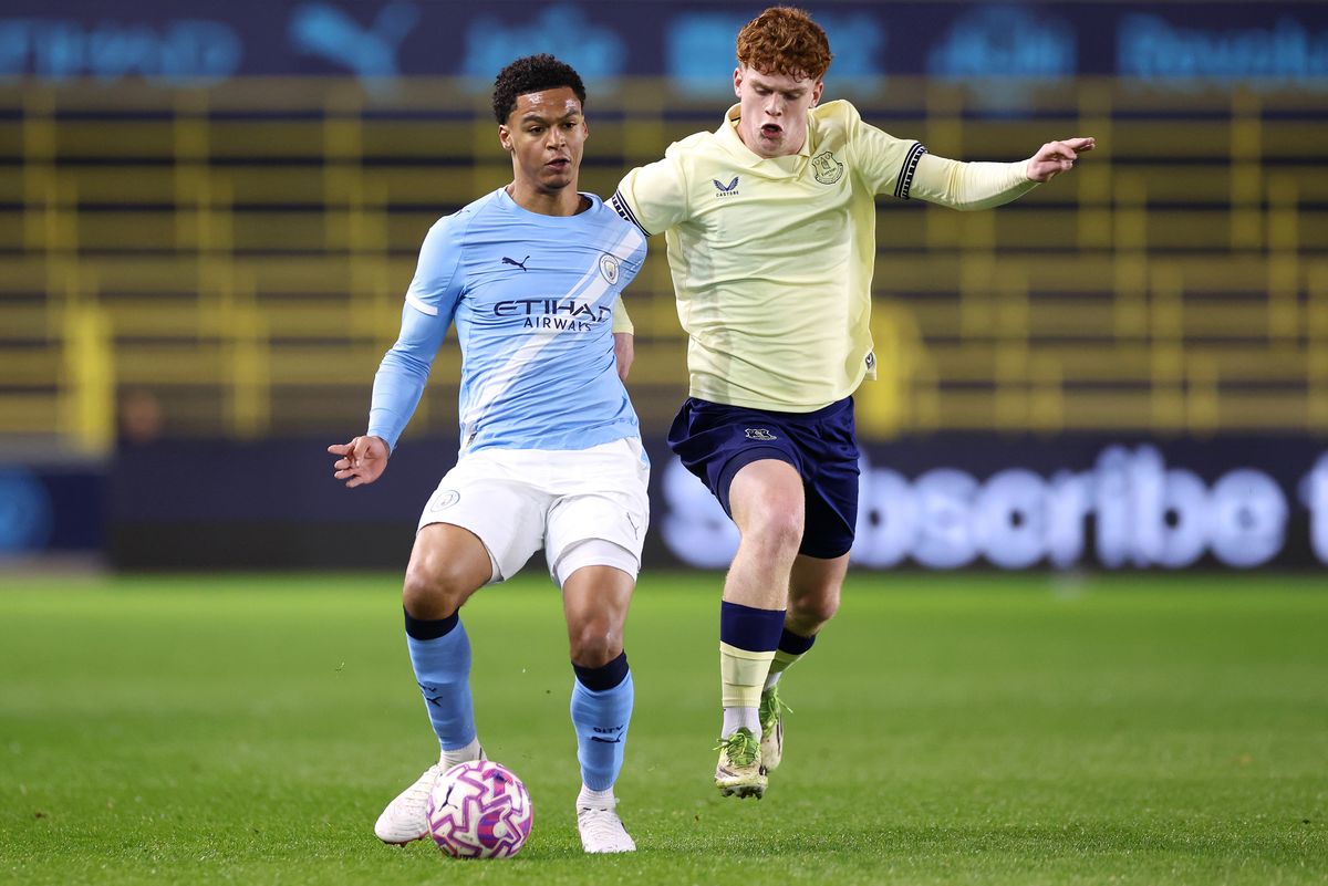 MANCHESTER, ENGLAND - MARCH 13: Leke Drake of Manchester City is challenged by Ceiran Loney of Everton during the FA Youth Cup Quarter Final match between Manchester City and Everton at Joie Stadium on March 13, 2026 in Manchester, England. (Photo by Lewis Storey/Getty Images)