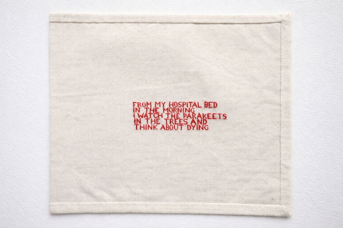 A piece of canvas with red text sewn into it. The text reads 'from my hospital bed in the morning I watch the parakeets and think about dying'. 