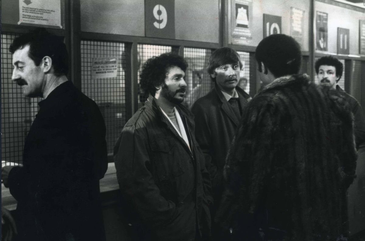 A scene from the first episode of Boys From The Blackstuff - Jobs For The Boys - with, left to right: Bernard Hill (Yosser Hughes), Michael Angelis (Chrissie Todd), Tom Georgeson (Dixie Dean) and, with his back to the camera, Alan Igbon (Loggo Lomond)