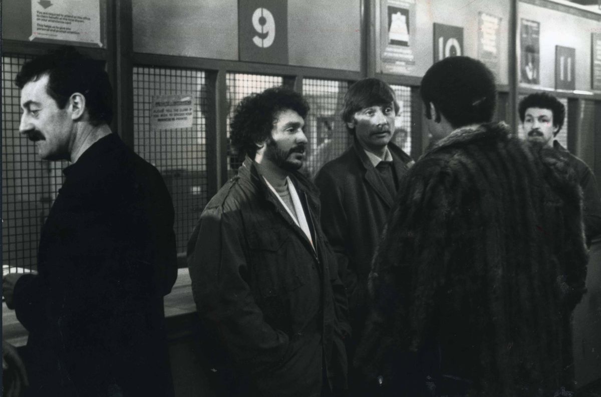 A scene from the first episode of Boys From The Blackstuff - Jobs For The Boys - with, left to right: Bernard Hill (Yosser Hughes), Michael Angelis (Chrissie Todd), Tom Georgeson (Dixie Dean) and, with his back to the camera, Alan Igbon (Loggo Lomond)