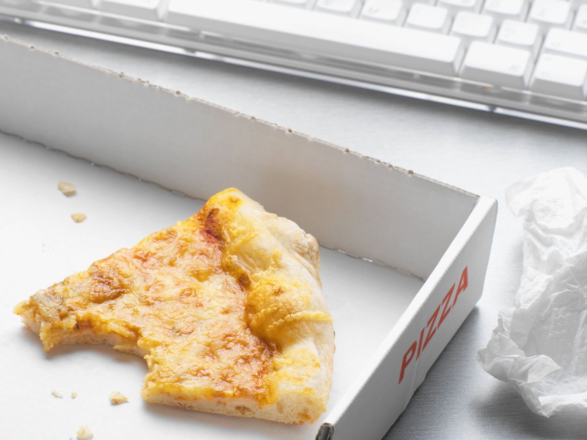 Generic image of a single, half-eaten slice of cheese and tomato pizza placed in a white box.
